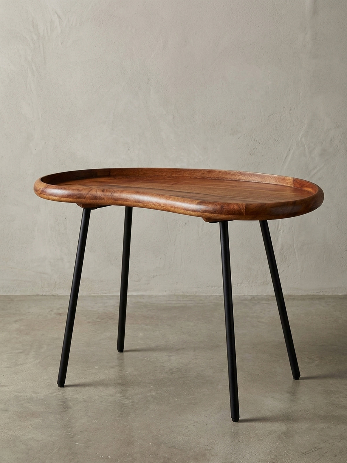 Kleiner Nierentisch aus massivem Sheesham-Holz mit schwarzen Metallbeinen. Der 71 cm breite Couchtisch im 50er Jahre Retro-Look präsentiert sich freigestellt vor weißem Hintergrund._