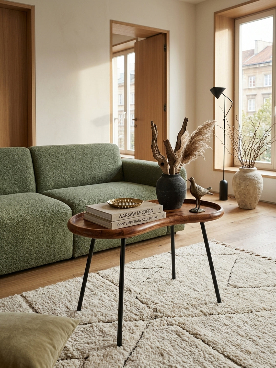 Eleganter Nierentisch aus massivem Sheesham-Holz in einem lichtdurchfluteten Wohnzimmer. Der 71x51x40 cm große Couchtisch im Retro-Design bringt warme Naturtöne ins moderne Interieur._