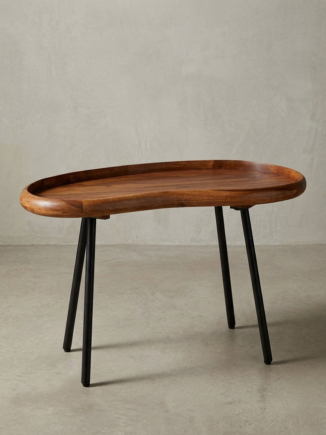 Kleiner Nierentisch im 50er Jahre Retro-Design freigestellt vor weißem Hintergrund. Der 71 cm breite Massivholz-Couchtisch besticht durch warme Holztöne und ausgestellte schwarze Beine._