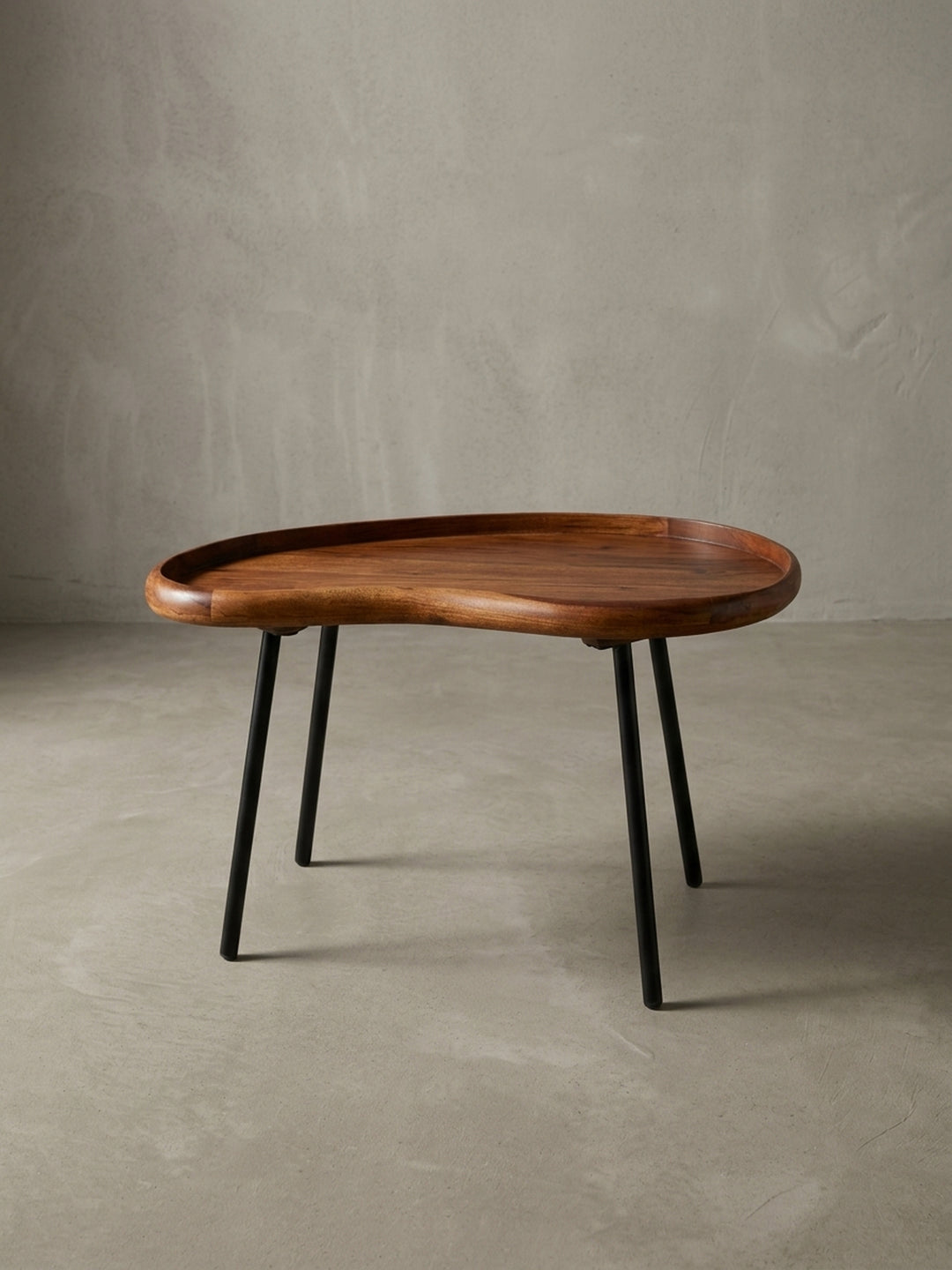 Kleiner Nierentisch im 50er Jahre Retro-Design freigestellt vor weißem Hintergrund. Der 71 cm breite Massivholz-Couchtisch besticht durch warme Holztöne und ausgestellte schwarze Beine._