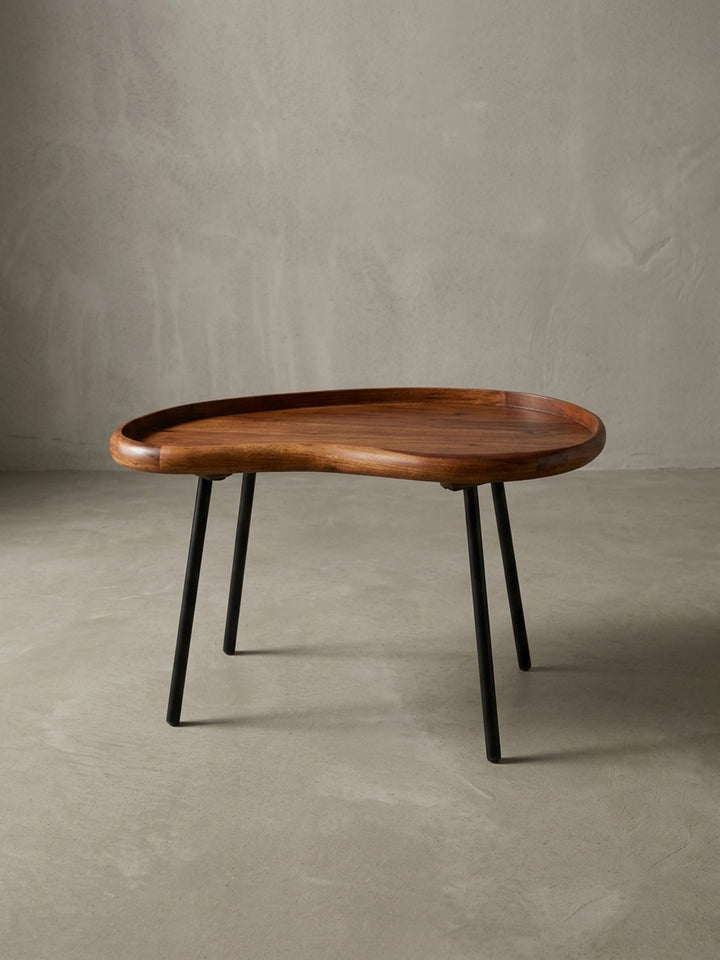 Kleiner Nierentisch im 50er Jahre Retro-Design freigestellt vor weißem Hintergrund. Der 71 cm breite Massivholz-Couchtisch besticht durch warme Holztöne und ausgestellte schwarze Beine._