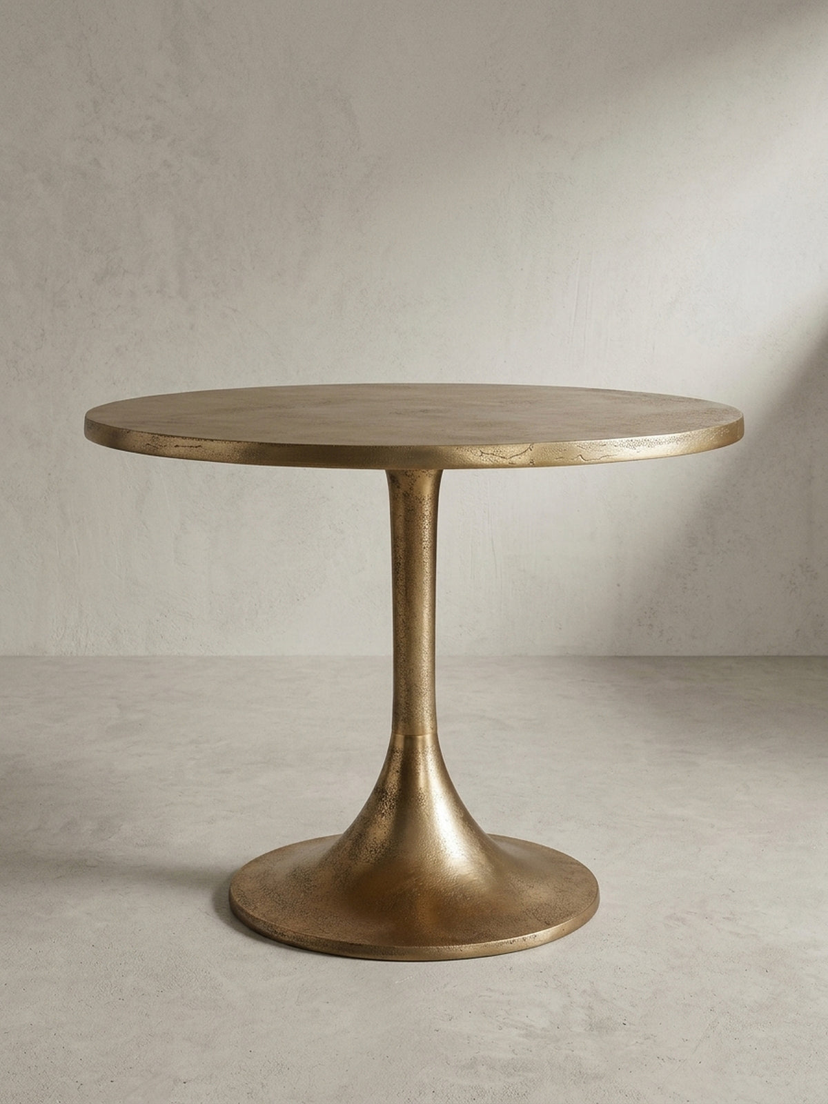 Makroaufnahme des Randes der Tischplatte eines goldenen Couchtisches, die die unregelmäßige Textur des Raw-Finish-Aluminiums zur Geltung bringt._