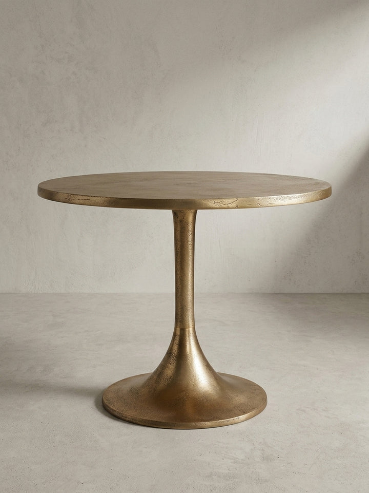 Makroaufnahme des Randes der Tischplatte eines goldenen Couchtisches, die die unregelmäßige Textur des Raw-Finish-Aluminiums zur Geltung bringt._
