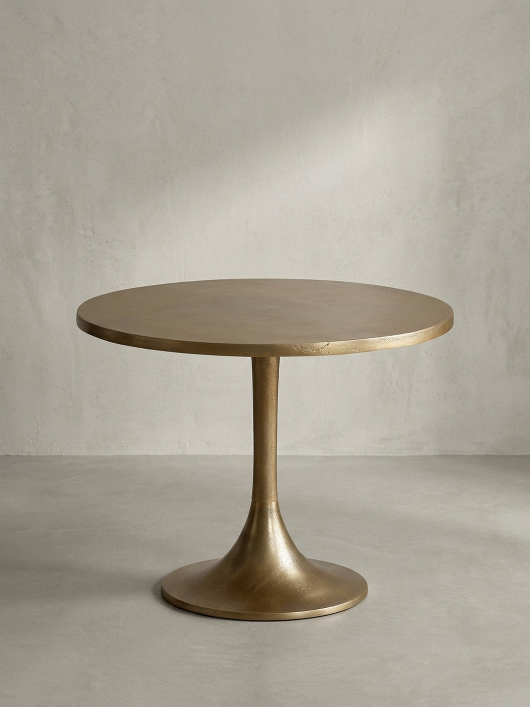 Seitenansicht des goldenen Couchtisches, die sein schlankes Profil und den elegant geschwungenen Trompetenfuß aus Aluminium hervorhebt._