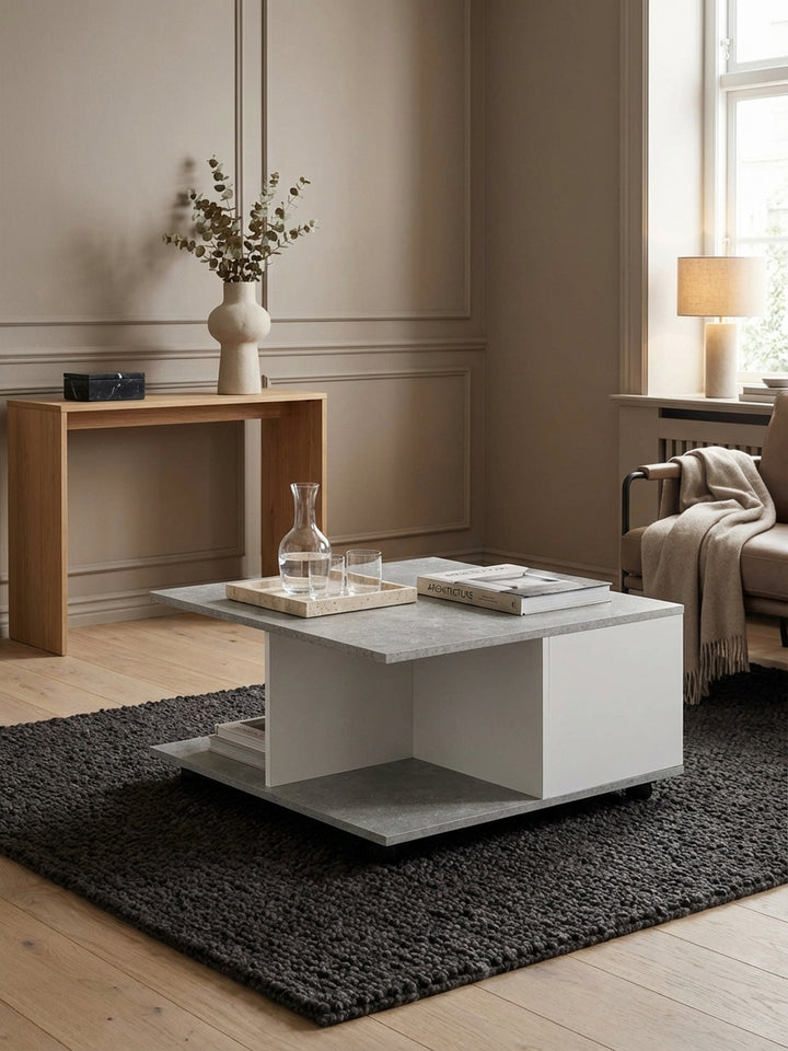 Moderner Couchtisch in Zementgrau und Weiß im Wohnzimmer, elegant kombiniert mit einem grauen Sofa und gelben Akzenten auf einem dunklen Teppich._