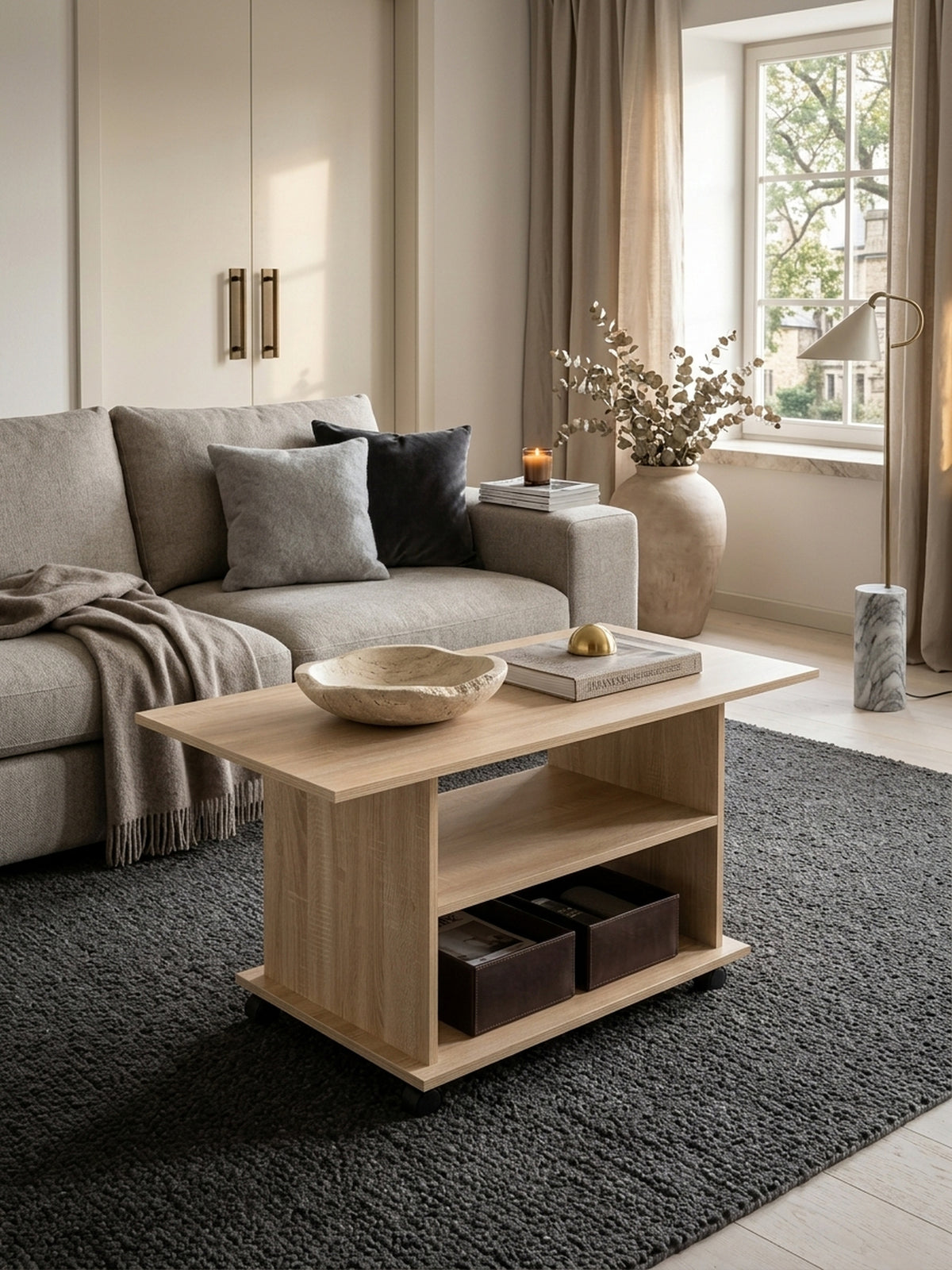 Moderner Couchtisch in Sonoma Eiche Optik auf Rollen, stilvoll inszeniert in einem eleganten Wohnzimmer. Der 95x51 cm große Sofatisch bietet viel Ablagefläche vor dem hellen Sofa._