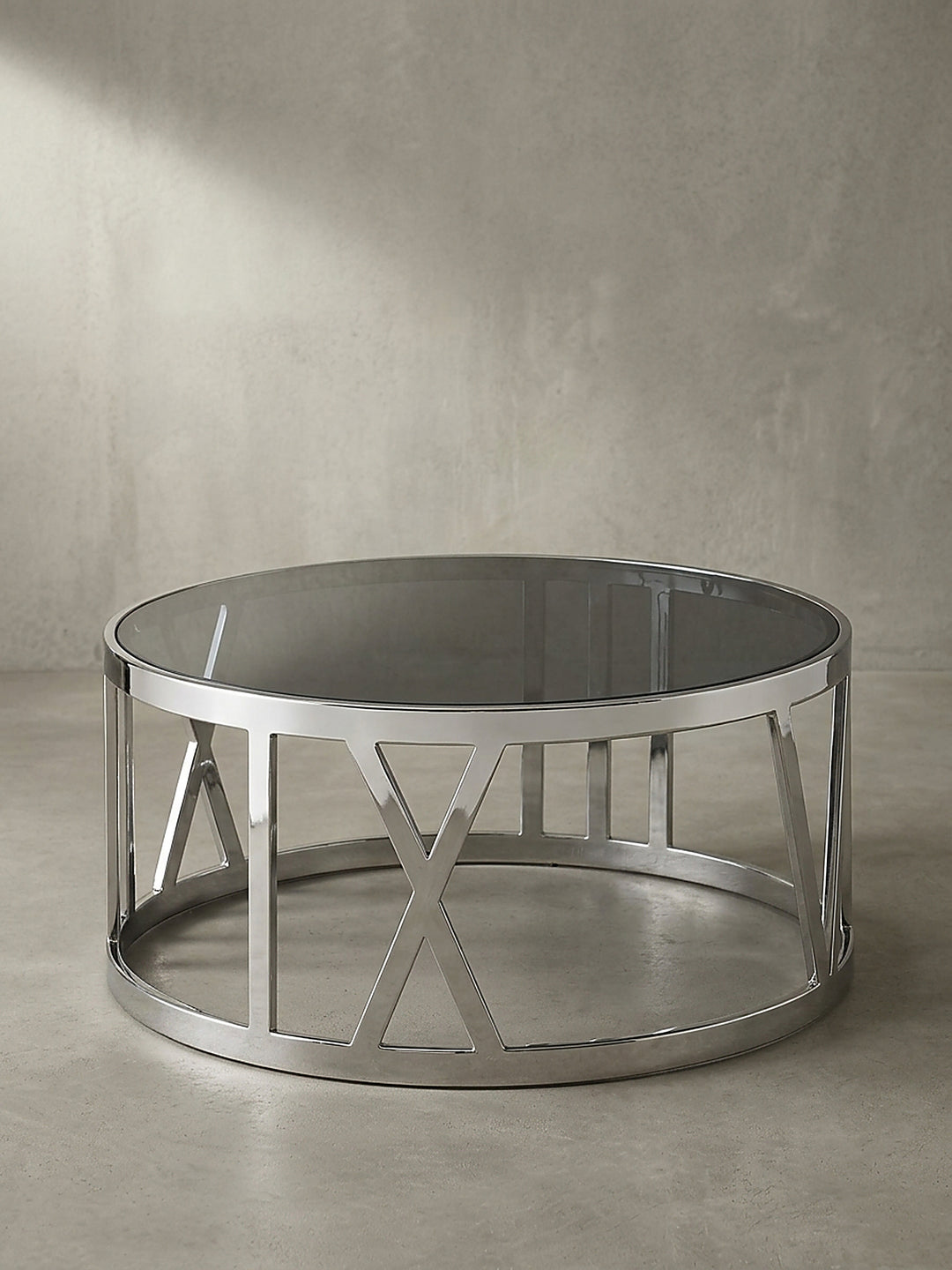 Design-Couchtisch im 3/4-Winkel, der die markante Kreuzstruktur des polierten silbernen Metallgestells unter der dunklen Glasfläche zeigt._