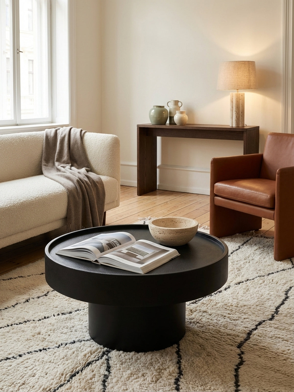 Ein offenes Magazin und eine Blumenvase stehen auf dem schwarzen runden Metall-Couchtisch und schaffen eine gemütliche Wohnatmosphäre._