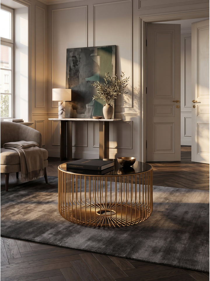 Runder Couchtisch aus goldenem Metall und schwarzem Glas 60x35 cm im luxuriösen Wohnzimmer auf dunkelgrauem Seidenteppich vor Boiserie-Wand_