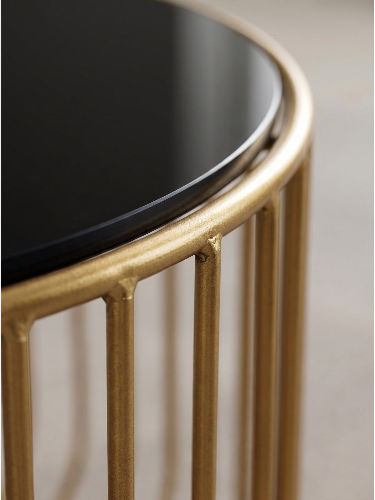 Nahaufnahme der spiegelnden schwarzen Glasplatte und der glänzenden goldenen Eisenstreben des Loungetisches, die markante Schatten werfen_