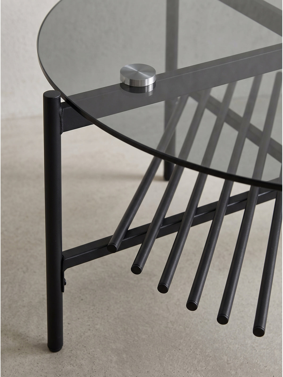 Übersichtsbild des kompakten runden Sofatisches im Industrial Design, das die harmonische Kombination aus dunklem Glas und Metallrohren zeigt.