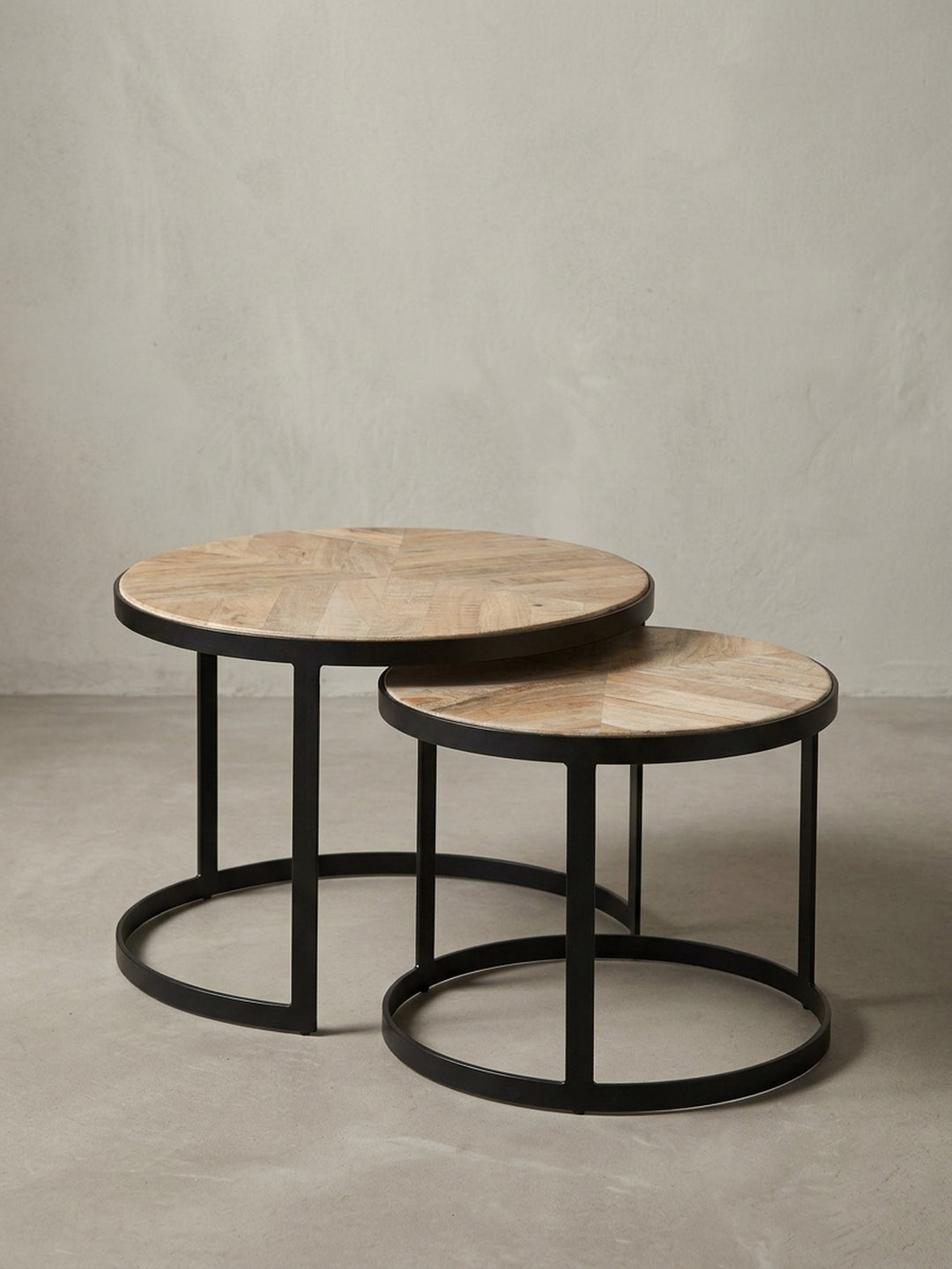 Nahaufnahme der Verbindung zwischen der Tischplatte aus Akazienholz und dem schwarzen Metallrahmen des runden Industrial Couchtischs._