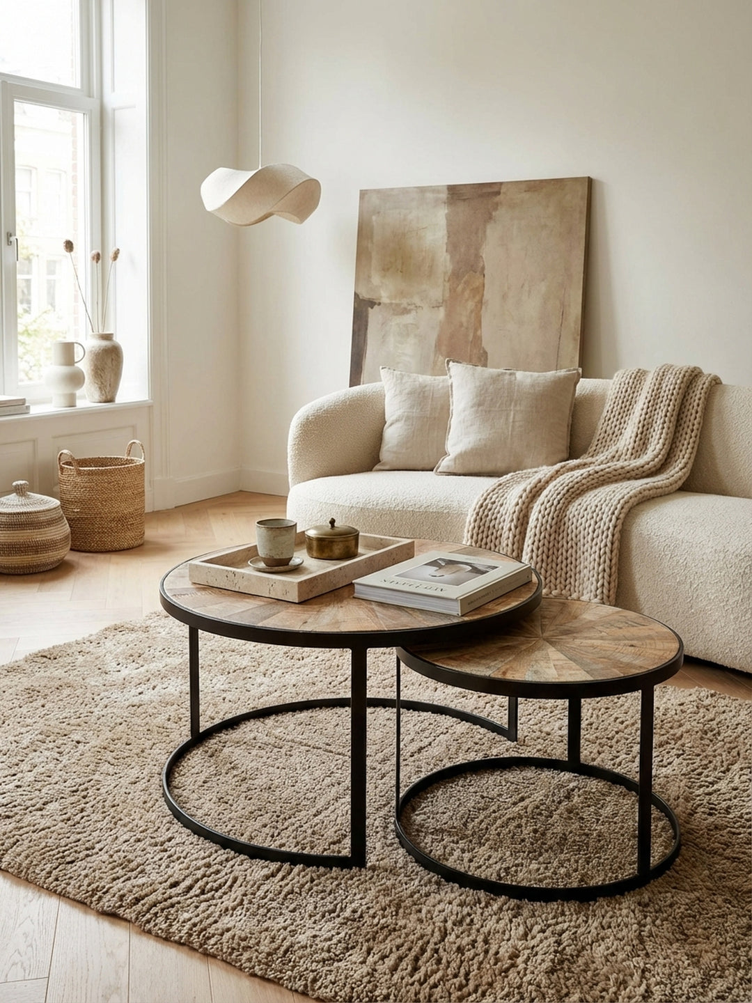 Runder Satztisch aus Mango Massivholz im organisch-modernen Wohnzimmer vor einem beigen Sofa, das natürliche Holz und schwarze Metallbeine schaffen eine warme Atmosphäre._