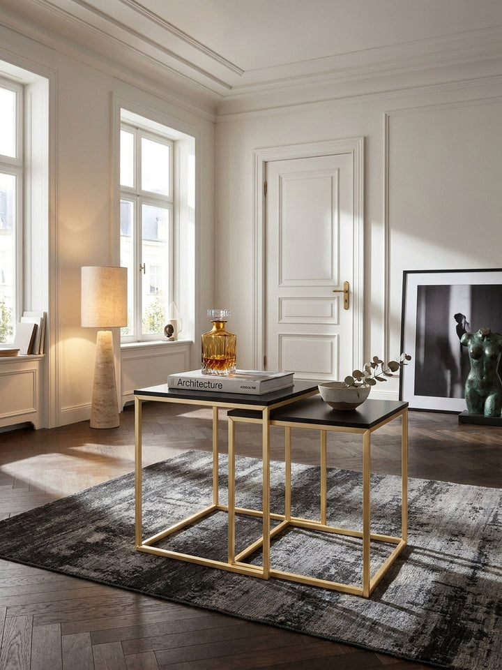 Ein eleganter Beistelltisch aus schwarzem MDF mit goldfarbenem Metallgestell 40x40x42 cm steht im modern-klassischen Wohnzimmer auf dunklem Eichenparkett._