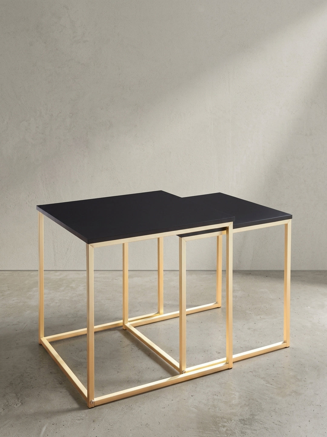 Quadratischer Beistelltisch mit goldfarbenem Metallrahmen und einer Tischplatte aus schwarz mattem MDF in sauberer Dreiviertelansicht vor weißem Hintergrund._