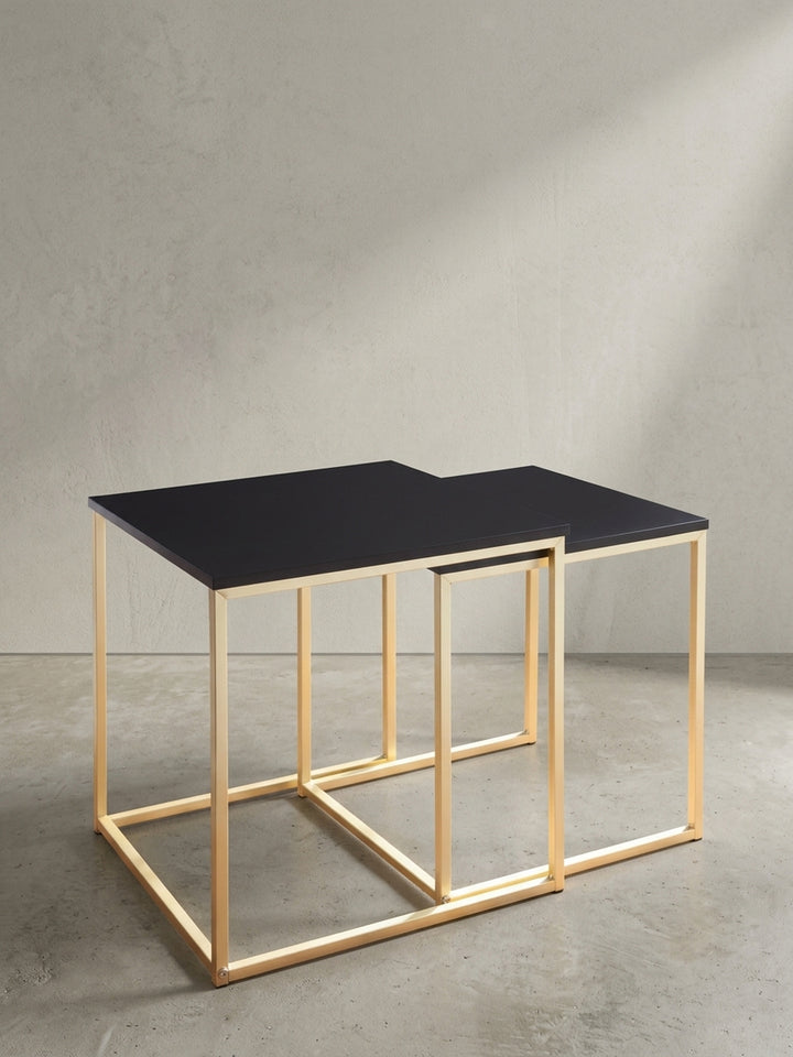 Quadratischer Beistelltisch mit goldfarbenem Metallrahmen und einer Tischplatte aus schwarz mattem MDF in sauberer Dreiviertelansicht vor weißem Hintergrund._