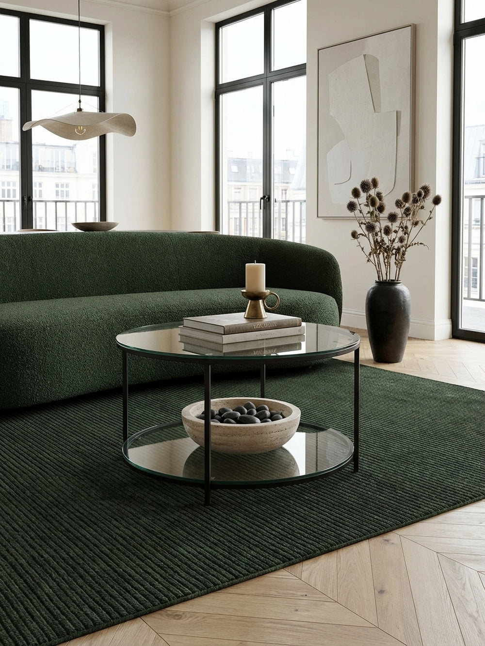 Moderner runder Couchtisch aus Glas und schwarzem Metall in einem stilvollen Wohnzimmer mit einem olivgrünen Sofa und einem texturierten Teppich._