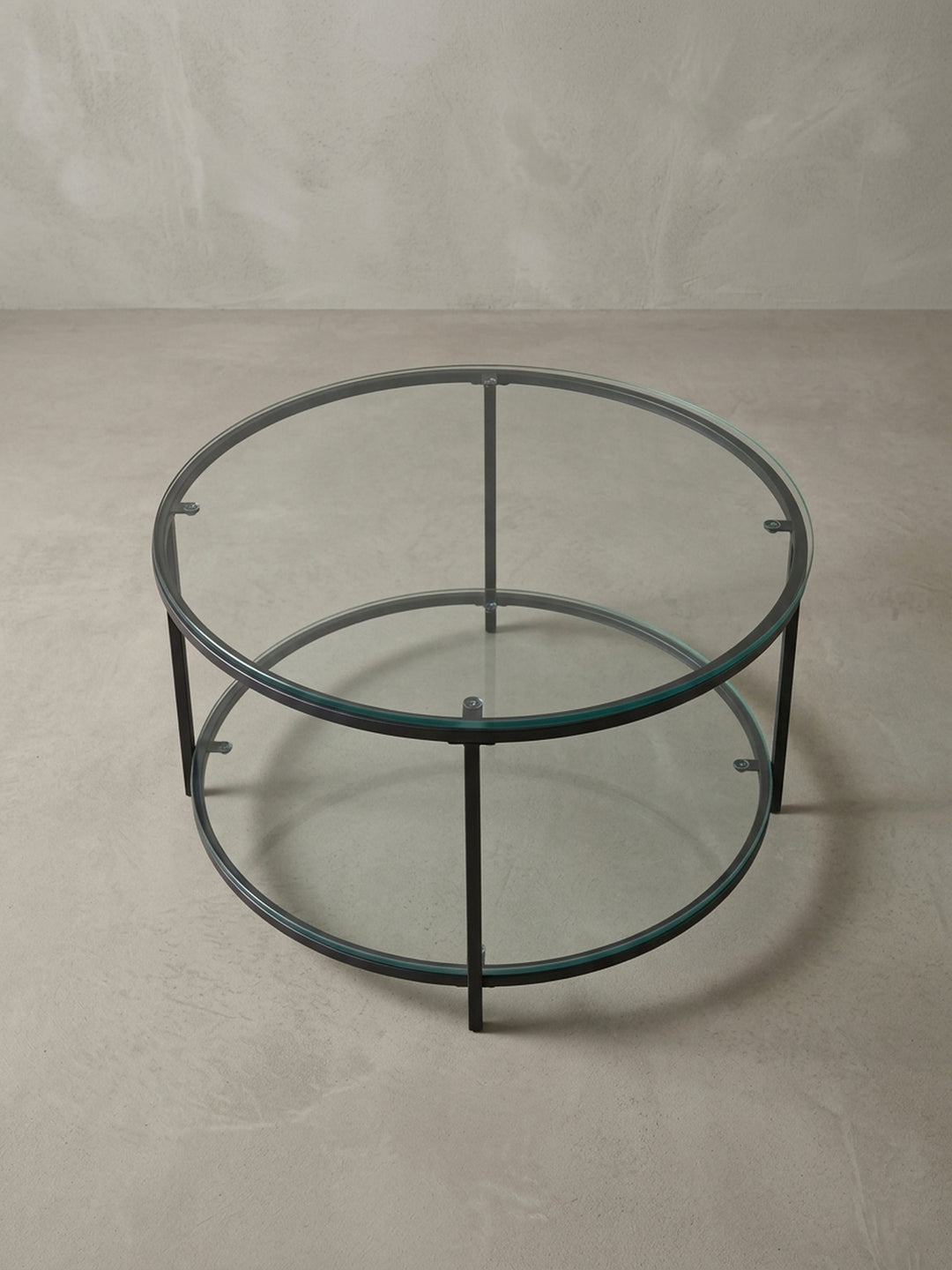Minimalistischer Loungetisch mit 80 cm Durchmesser aus Glas und Stahl, aus einer leicht erhöhten Perspektive fotografiert, um die runde Form zu betonen._
