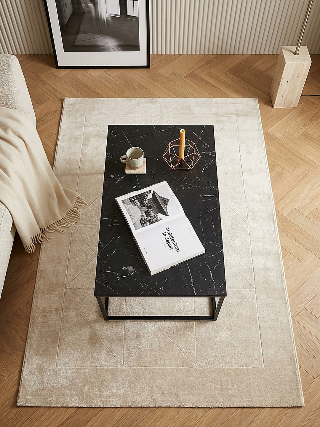 Luftaufnahme des 100x60x40 cm großen Sofatisches in Schwarz, der klare geometrische Kontraste zum strukturierten Lounge-Sofa und dem anthrazitfarbenen Wollteppich im modernen Raum bildet_