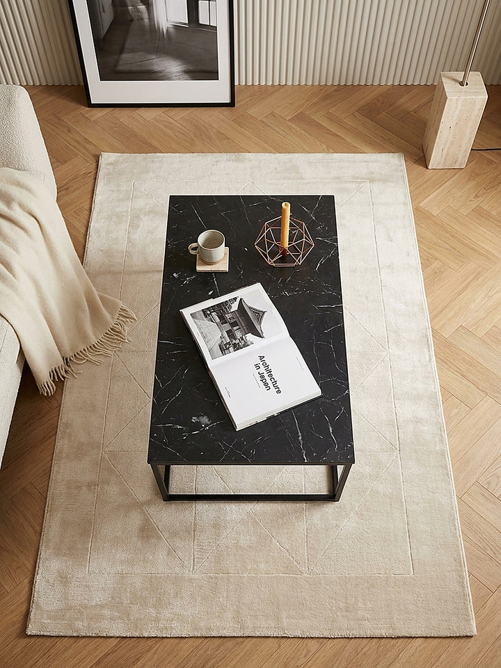 Luftaufnahme des 100x60x40 cm großen Sofatisches in Schwarz, der klare geometrische Kontraste zum strukturierten Lounge-Sofa und dem anthrazitfarbenen Wollteppich im modernen Raum bildet_