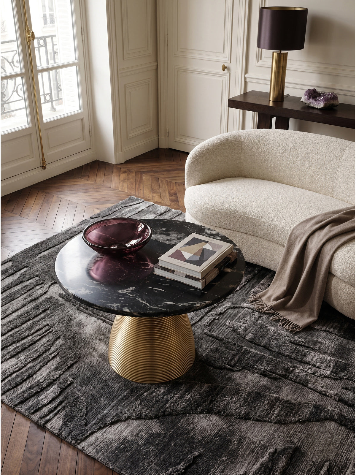Draufsicht auf den runden Marmortisch mit markanter weißer Maserung neben einem cremefarbenen Bouclé-Sofa im hellen Haussmann-Stil Interior