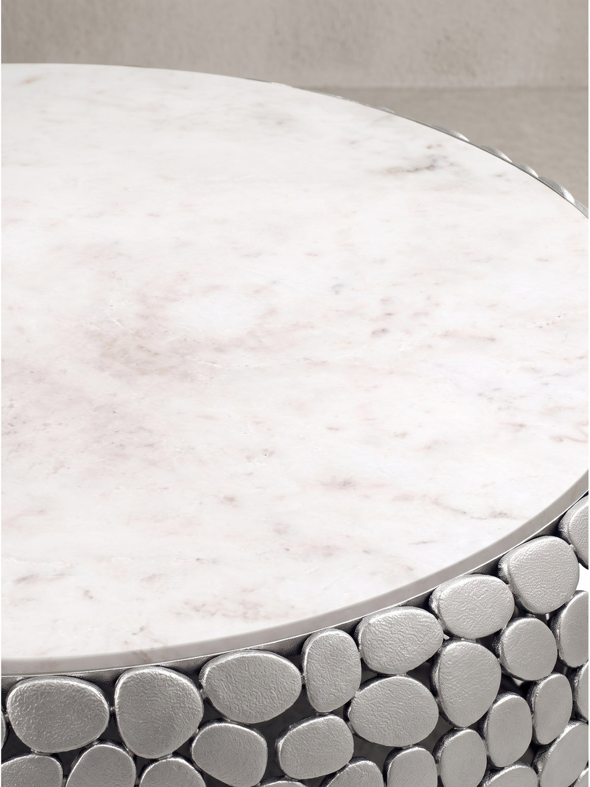 Gesamtdesign des skulpturalen Couchtisches aus echtem weißen Marmor und strukturiertem Aluminium freigestellt auf Weiß._