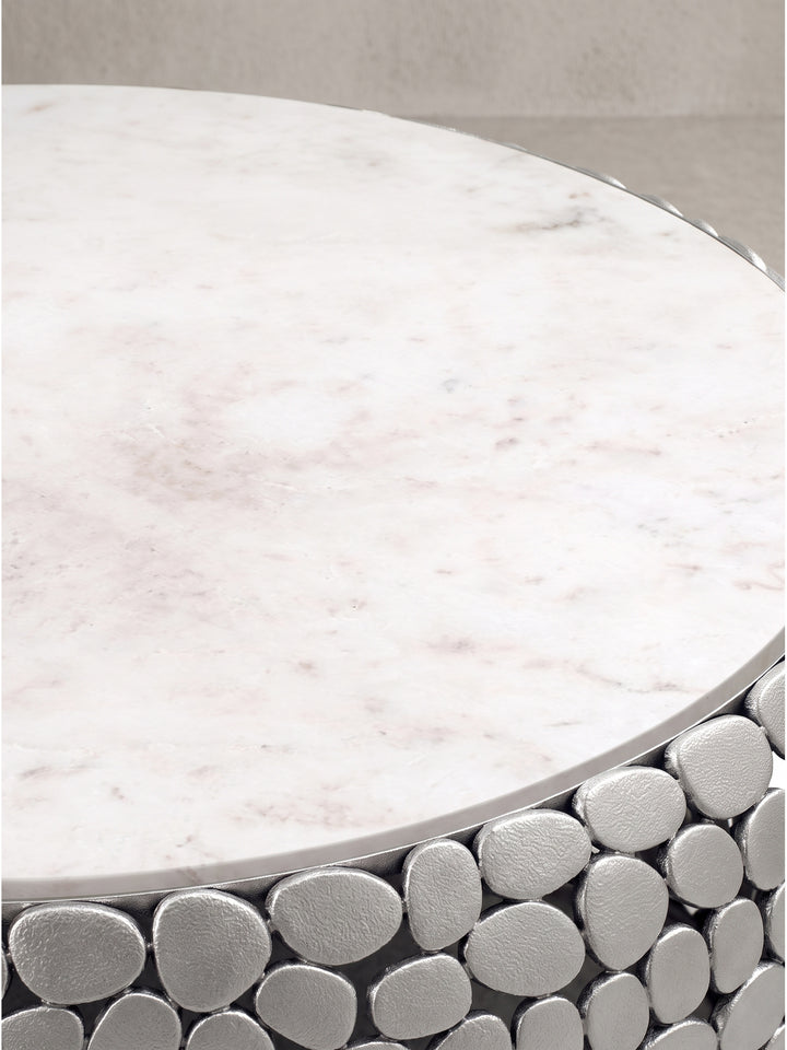 Gesamtdesign des skulpturalen Couchtisches aus echtem weißen Marmor und strukturiertem Aluminium freigestellt auf Weiß._