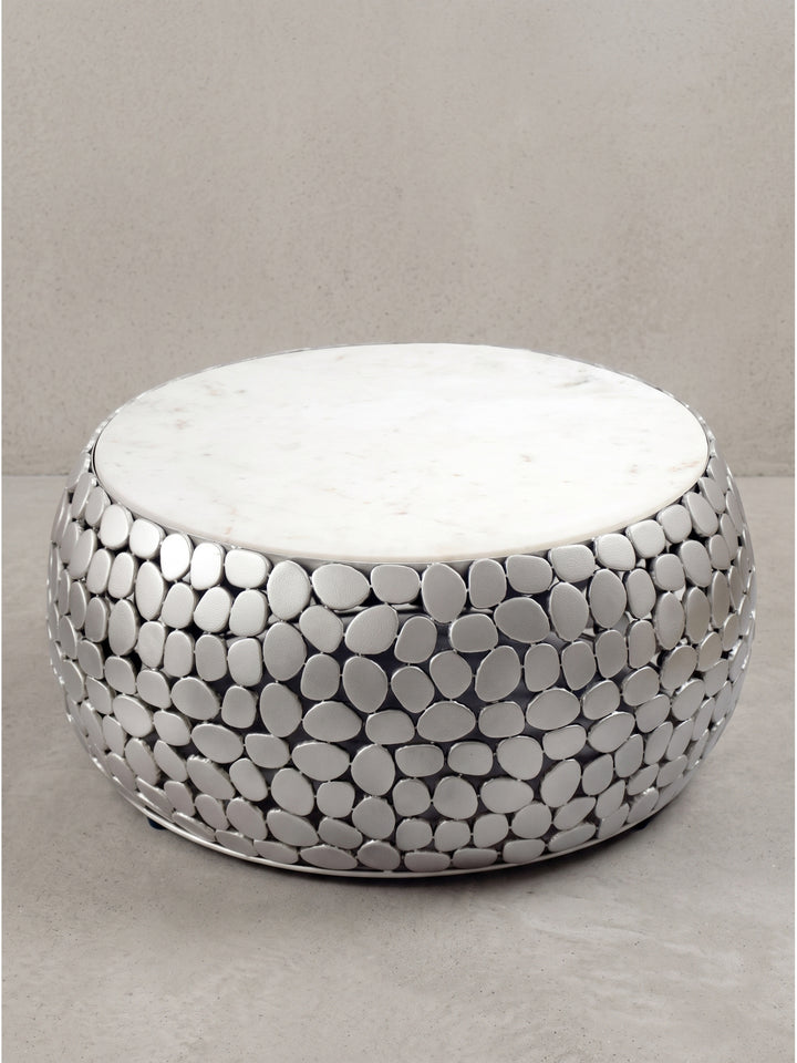 Runder Couchtisch mit weißer Marmorplatte und Kieselstein-Optik Korpus aus pulverbeschichtetem Aluminium in Silber frontal vor weißem Hintergrund._