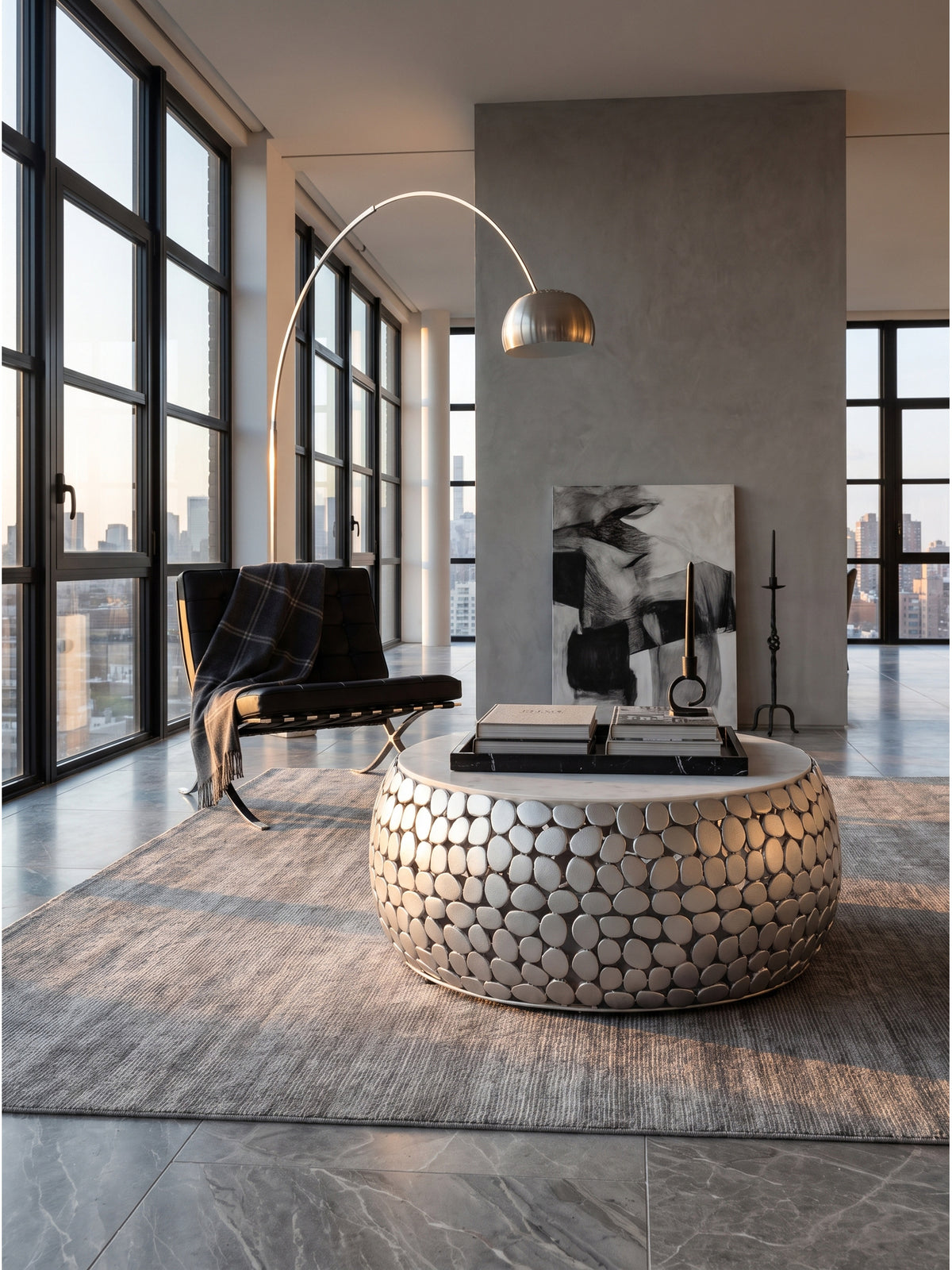 Runder Design Couchtisch aus silbernem Aluminium und weißem Marmor 66x32 cm im puristischen Wohnzimmer vor einer fugenlosen Mikrozementwand._