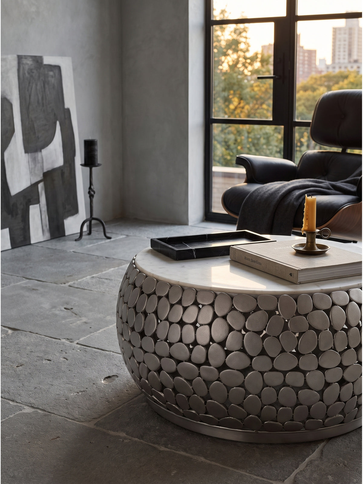 Runder weißer Marmor Sofatisch dekoriert mit einem schwarzen Naturstein-Tablett und einem Architektur-Bildband im modernen Loft._