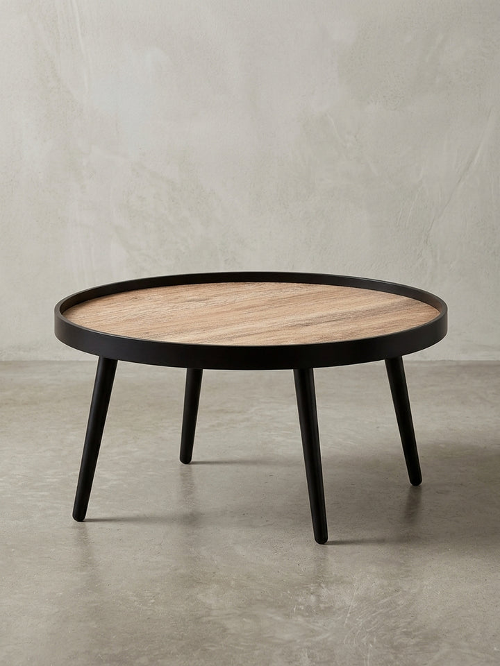 Moderner Couchtisch rund 76 cm Durchmesser, freigestellt mit brauner Tischplatte im Holzlook und mattschwarzen Beinen aus Massivholz._