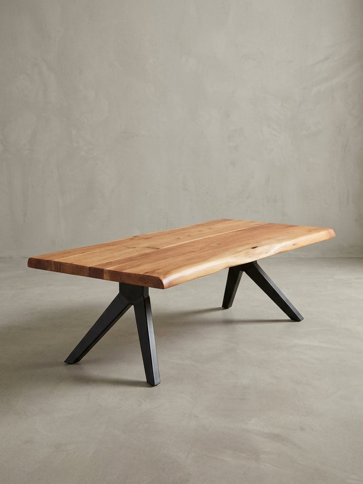 Seitenansicht des Stubentisches im Industrial-Stil, die das schlanke Profil der schwarzen Metallbeine und die massive Präsenz der Akazienholzplatte betont._
