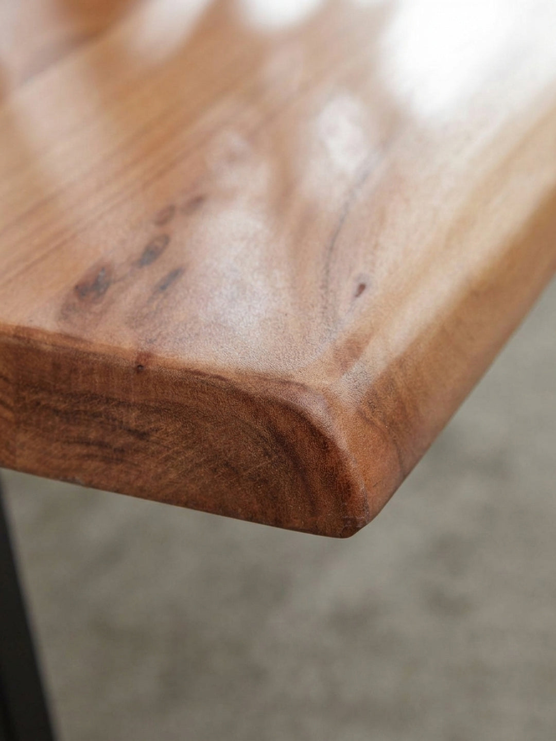 Alternativer Blickwinkel auf den massiven Sofatisch, der die unregelmäßige, organische Form der Baumkante und die warme Farbe des Akazienholzes hervorhebt._