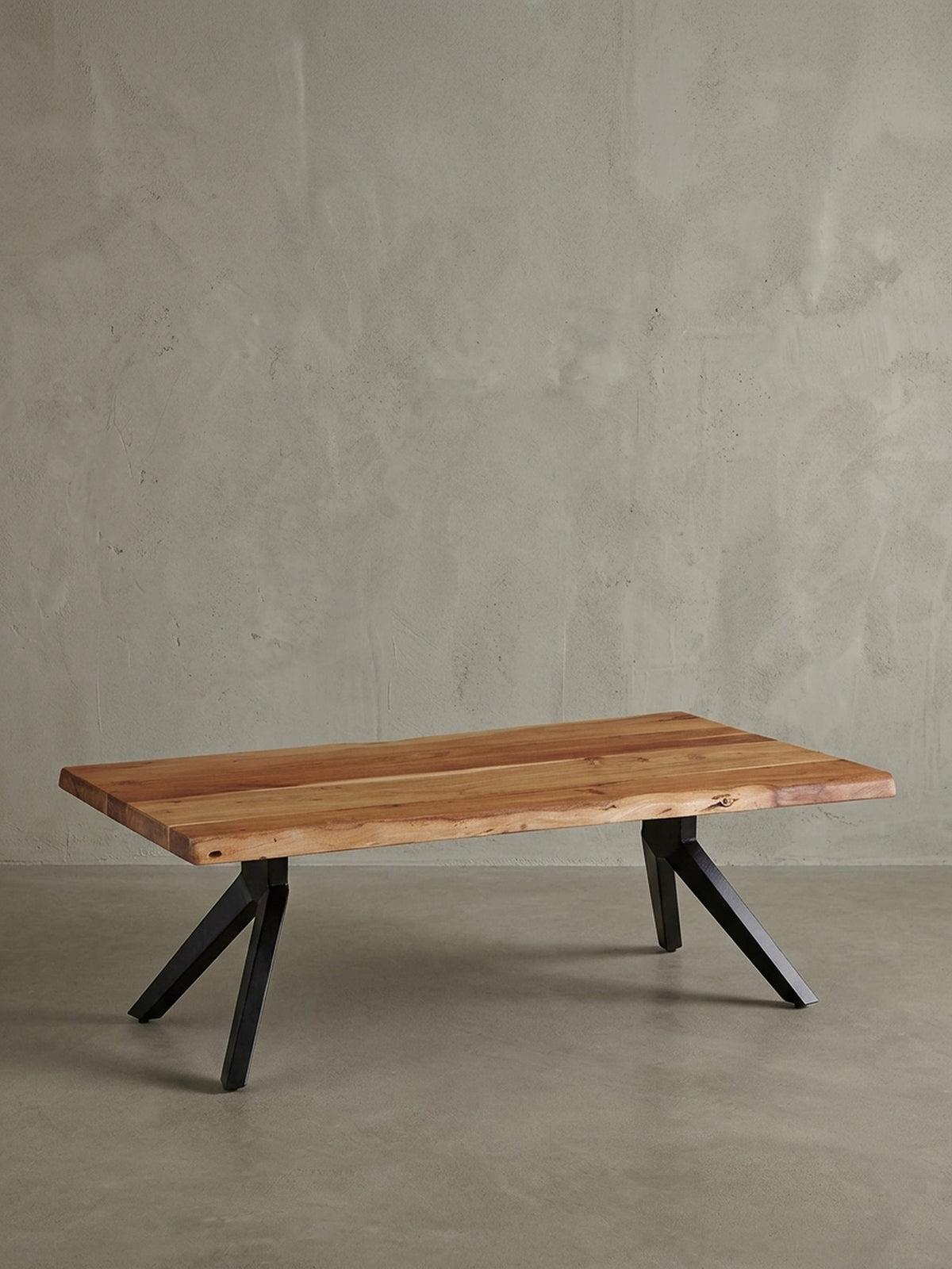 Freigestellter Industrial Couchtisch aus Akazienholz mit schwarzen Metallbeinen, Frontansicht, die die robuste 4 cm dicke Tischplatte mit Baumkante präsentiert._