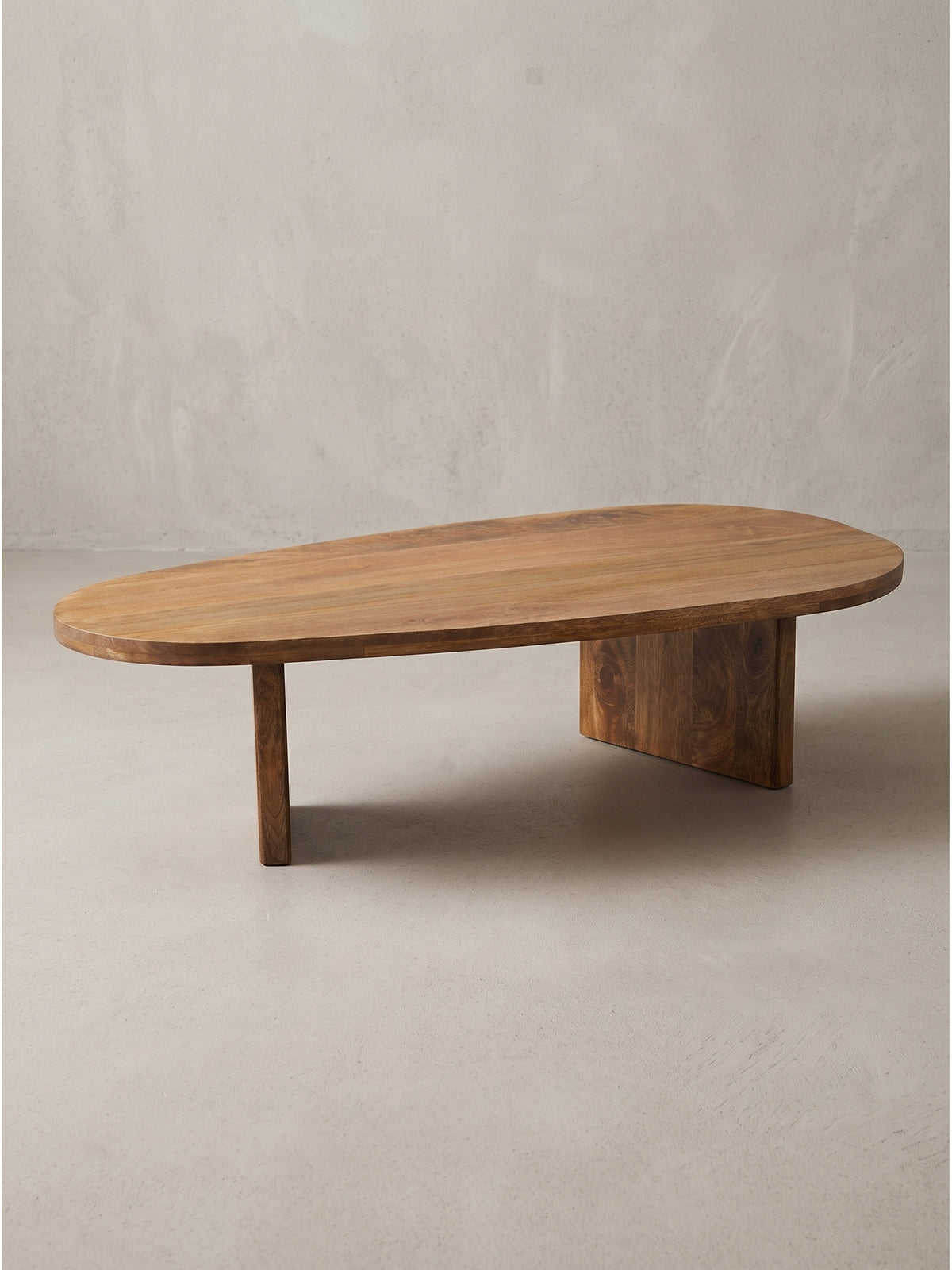 Organisch geformter Couchtisch aus Mango Massivholz freigestellt vor weißem Hintergrund mit klar erkennbarem asymmetrischem Beingestell._