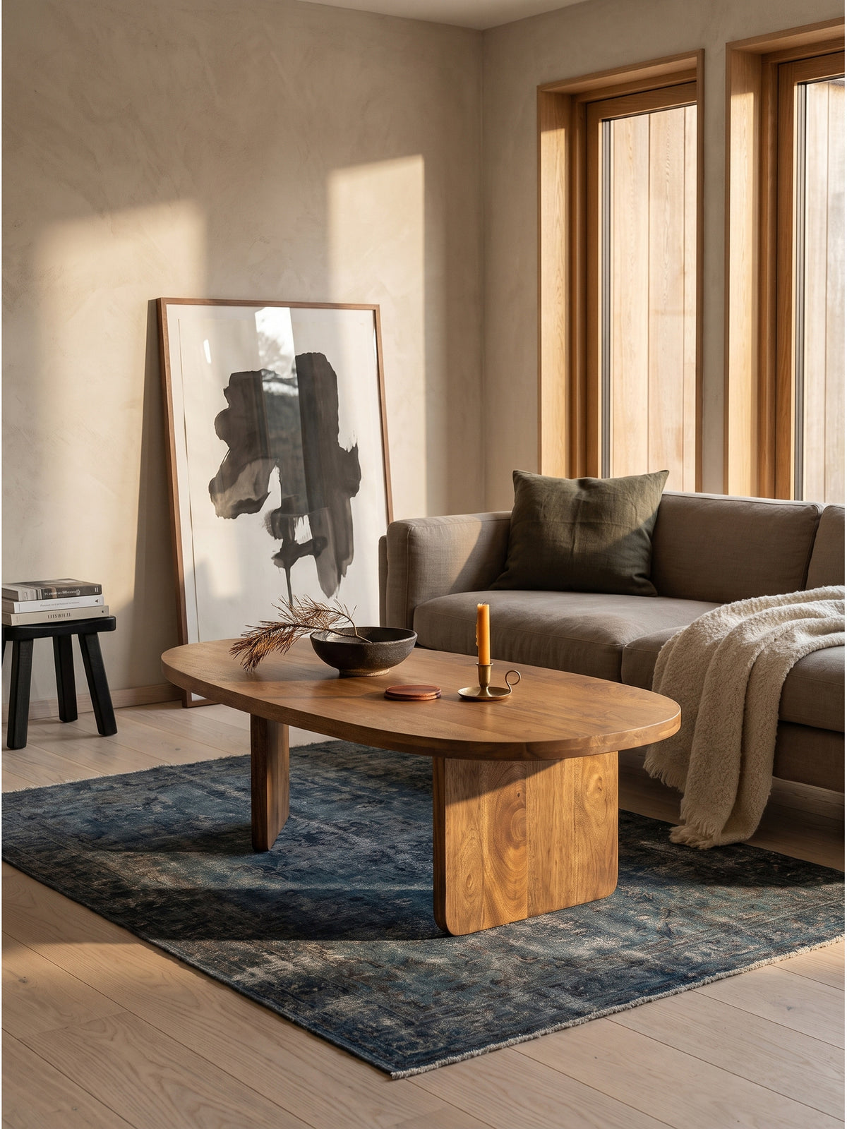 Bodennaher Couchtisch mit Plattenfuß in eleganter Kombination mit einem voluminösen Sofa und einer dunklen Leinen-Stehleuchte._