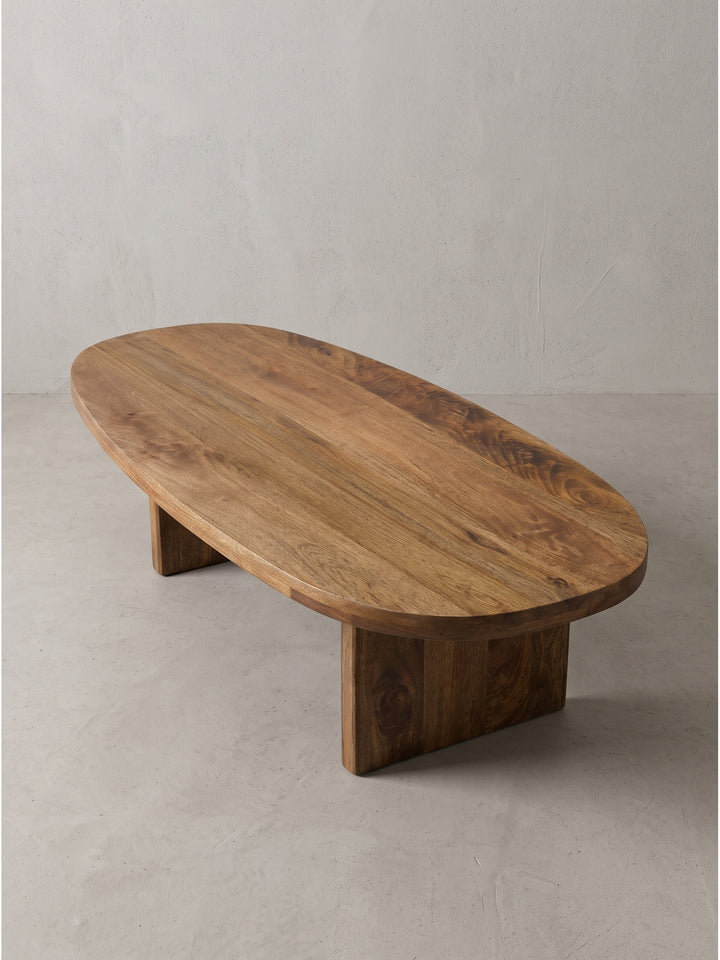 Handgefertigter flacher Beistelltisch aus massivem Holz im seitlichen Winkel, der die markante abgerundete Formgebung deutlich macht._