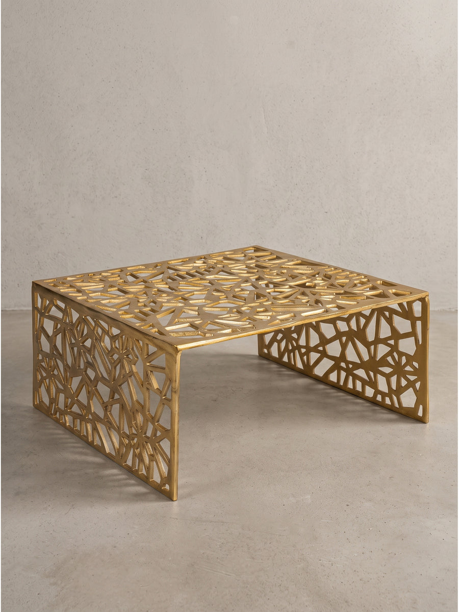 Goldener Couchtisch aus Aluminium 60x60x31 cm in Schrägansicht freistehend vor weißem Hintergrund mit asymmetrischen Durchbrüchen._