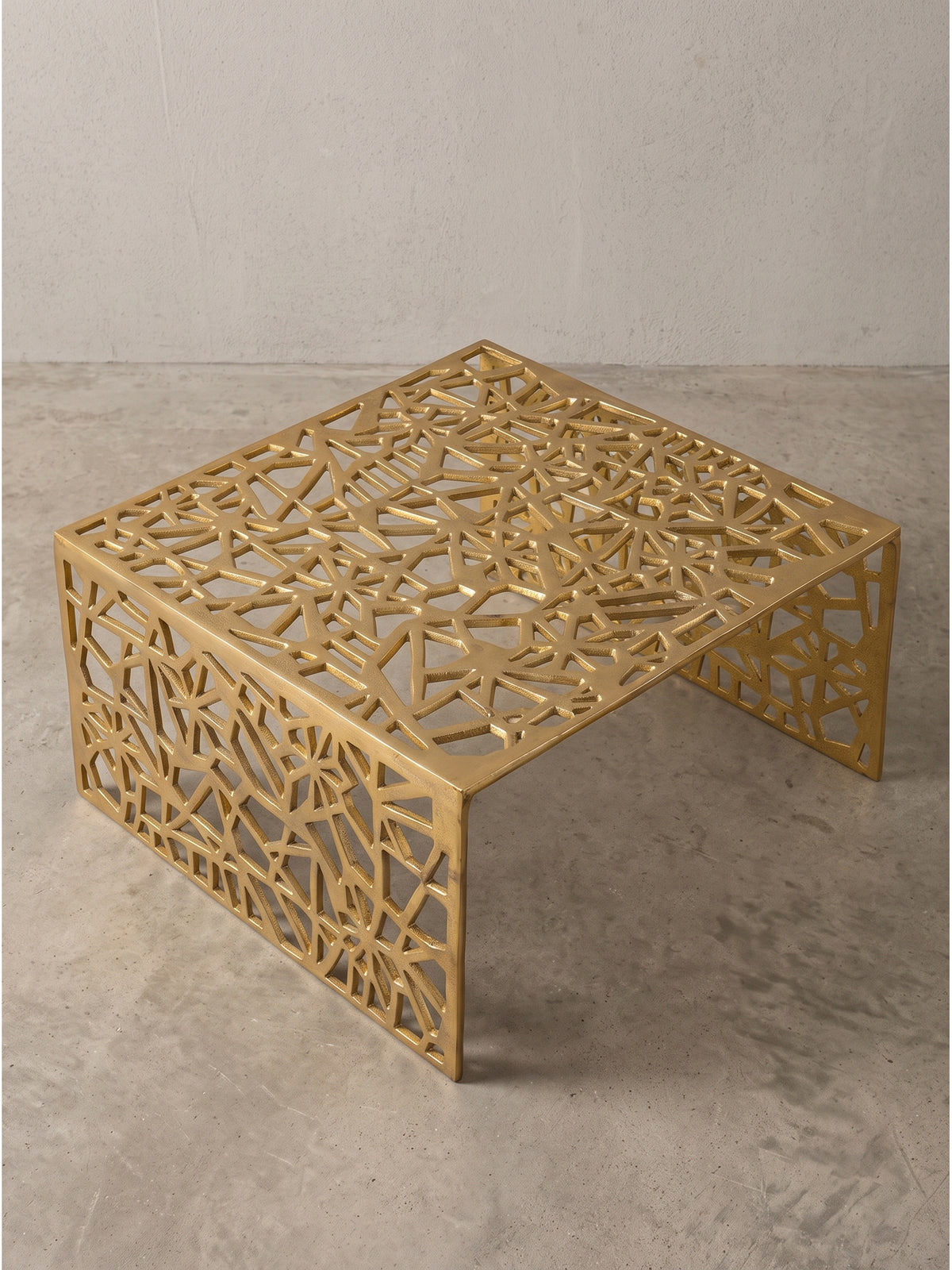 Sofatisch aus Metall quadratisch mit geometrischem Wabenmuster, die seitliche Ansicht zeigt die offene Brückenkonstruktion.