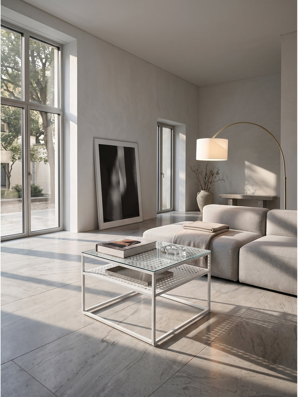 Minimalistischer Couchtisch aus Klarglas und weißem Metallgestell 60x60 cm im puristischen Wohnzimmer auf kühlem Kalksteinboden._