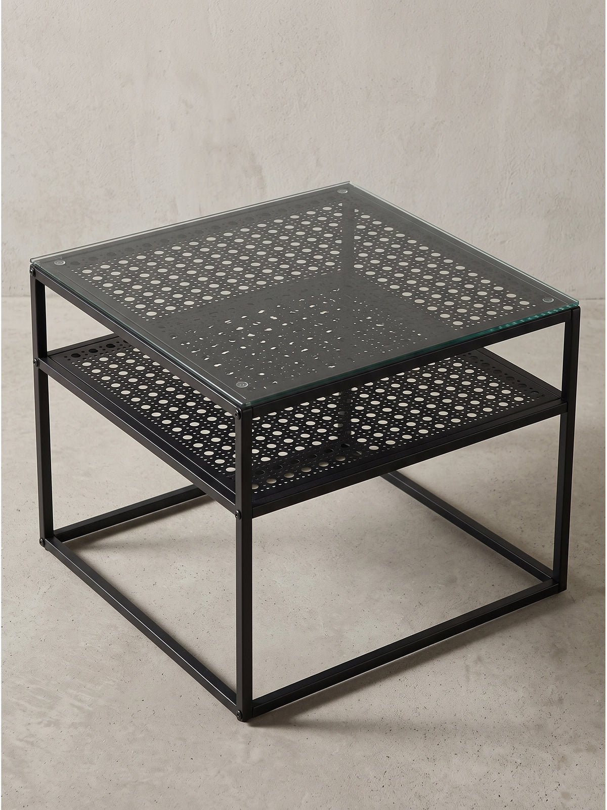 Seitenansicht des modernen Couchtisches mit schwarzem Metallgestell und transparenter Sicherheitsglasplatte_
