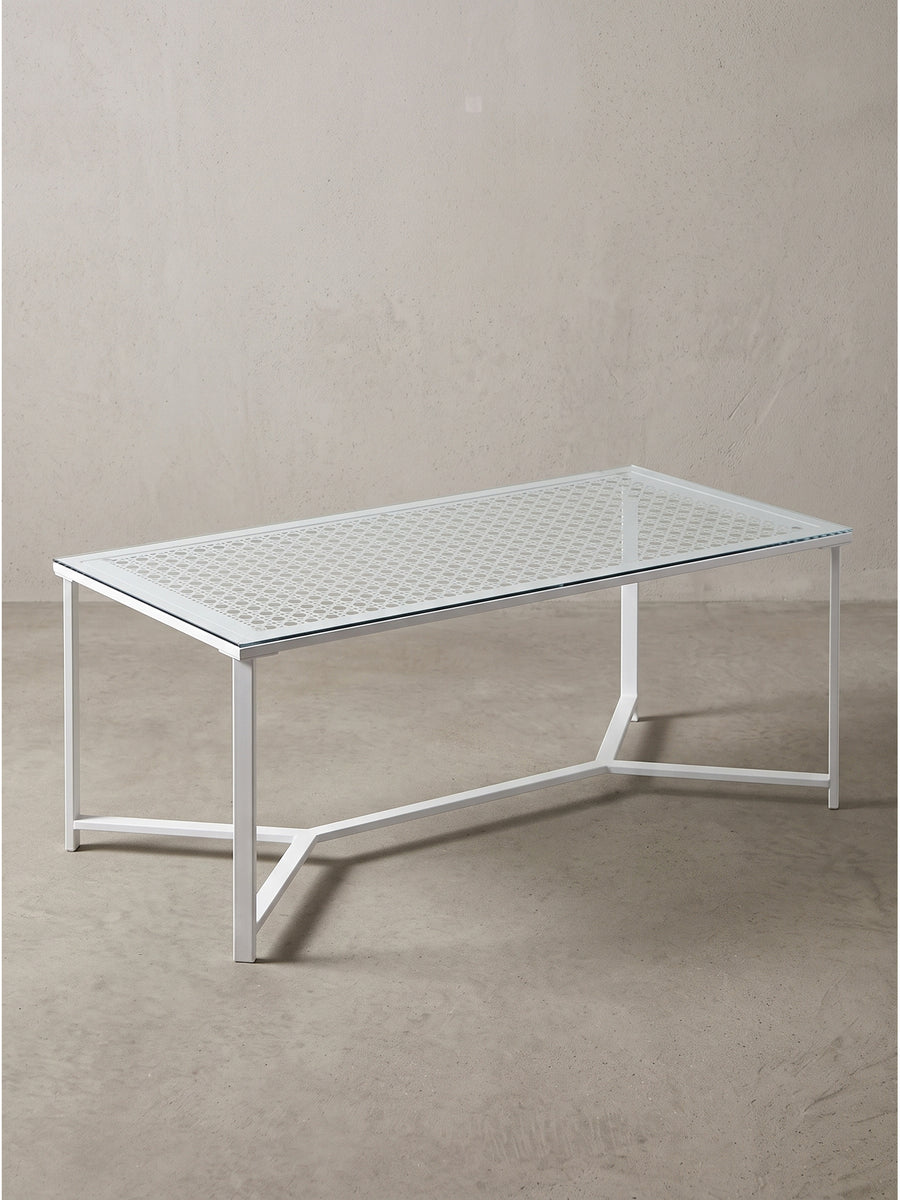 Rechteckiger Couchtisch aus Einscheibensicherheitsglas mit markantem weißem Metallgestell und geometrisch bedruckter Oberfläche in der Frontalansicht_