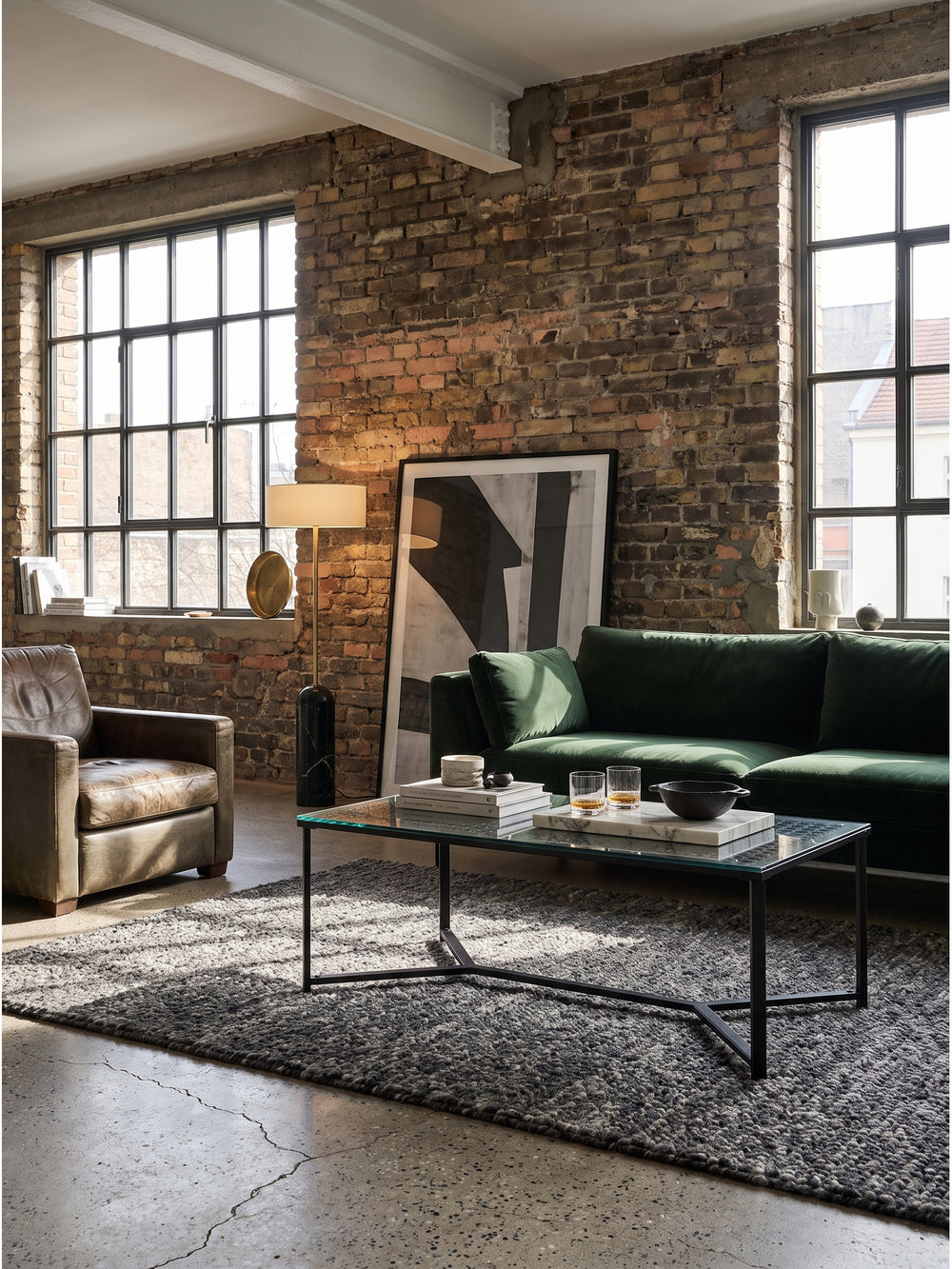 Rechteckiger Couchtisch aus Glas und Metall im industriellen Wohnzimmer mit Cognac-Ledersofa vor einer gekalkten Backsteinwand_