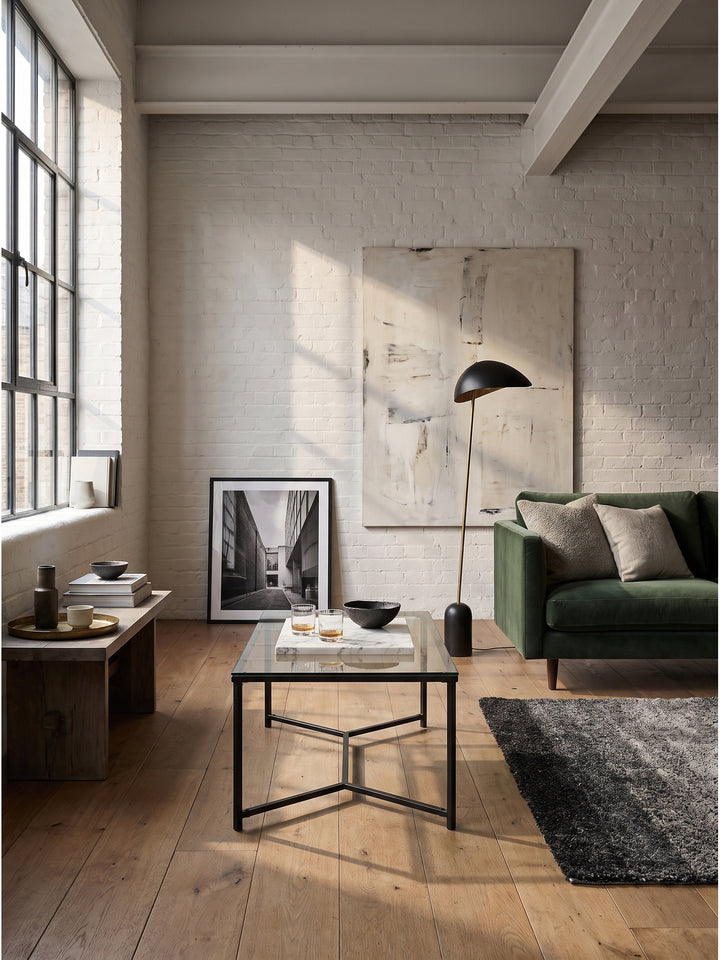 Stylischer Couchtisch mit einer Platte aus gemustertem Glas, dekoriert mit Marmortablett und Whiskeygläsern_