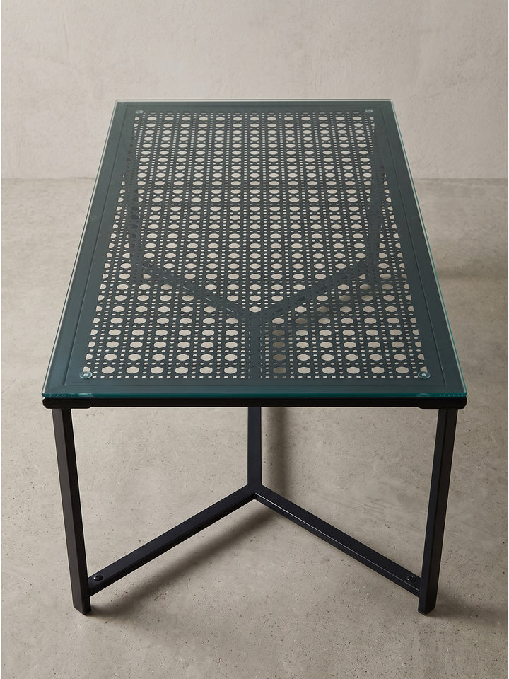 Moderner Couchtisch mit filigranen Metallbeinen und schwarz gemusterter Glasplatte schräg von links betrachtet_