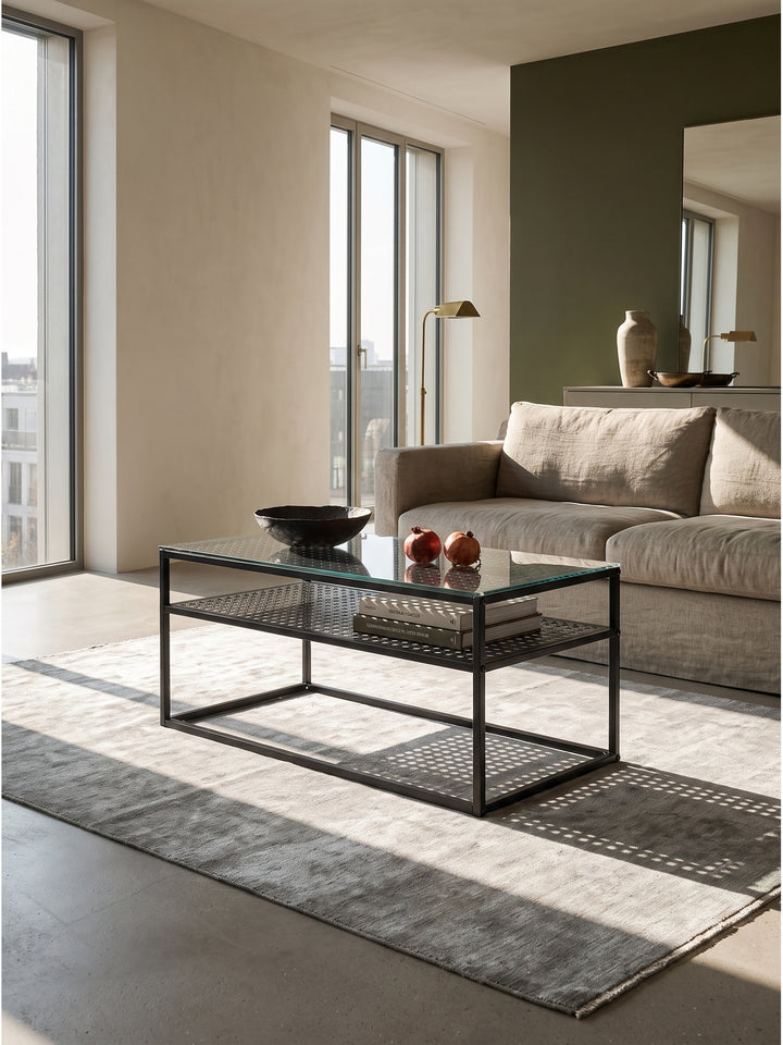 Moderner Couchtisch aus Glas und schwarzem Metall 100x50x45 cm zentral platziert im Wohnzimmer vor einer dunkelgrünen Akzentwand_