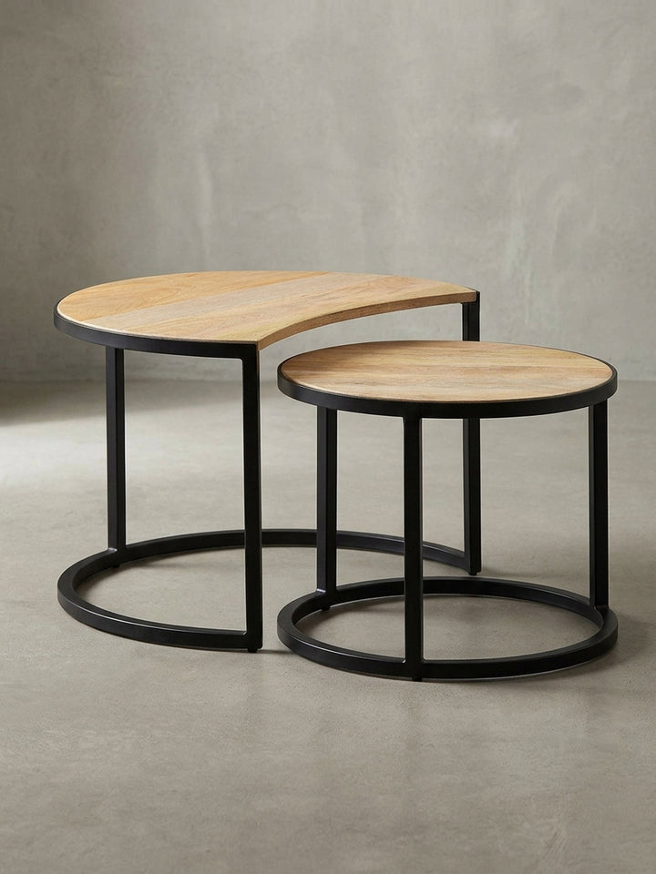 Schräger Blick auf den zweiteiligen Wohnzimmertisch im Industrial Design. Das massive Mangoholz der Platten harmoniert mit dem robusten, pulverbeschichteten Eisengestell._