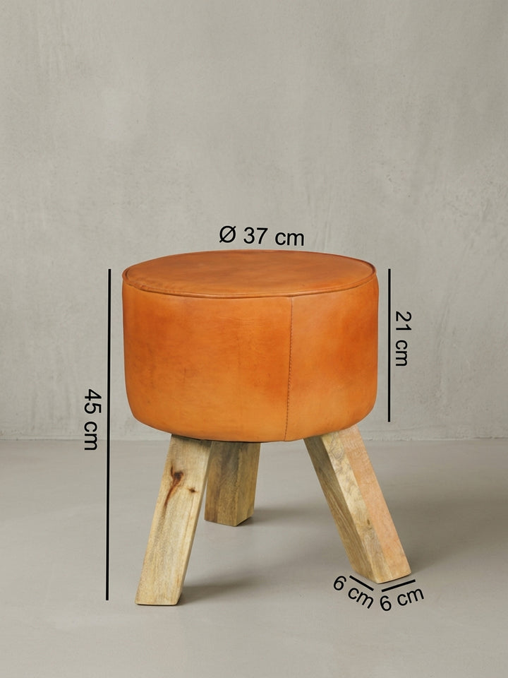 Detailansicht der Rückseite des kleinen Holzhockers. Die saubere Verbindung zwischen dem zylindrischen Lederpolster und dem Mangoholzgestell zeigt die handwerkliche Präzision._