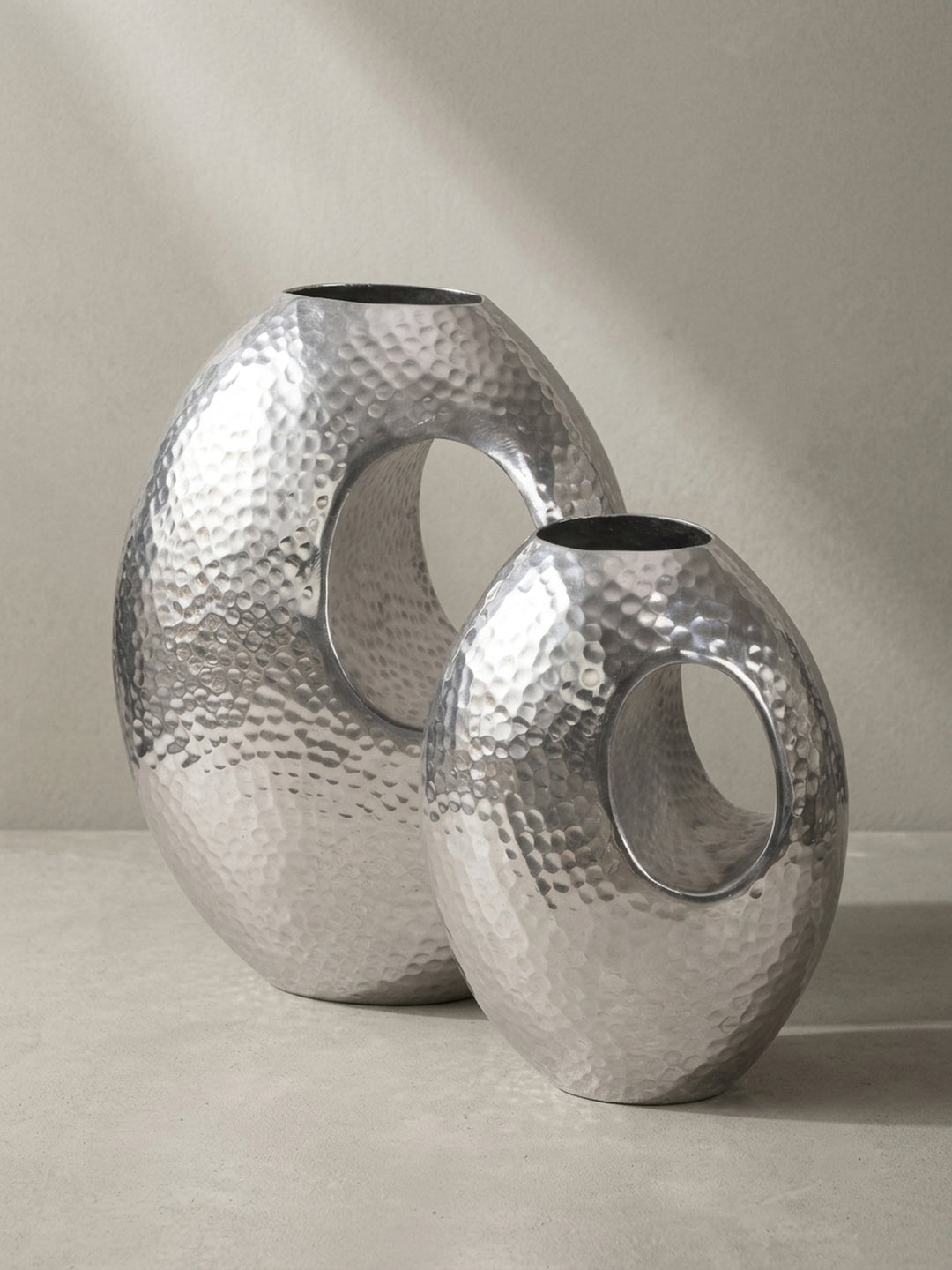 Nahaufnahme der runden Öffnung und des handgefertigten Randes der eleganten Aluminium-Bodenvase in Silber-Optik._