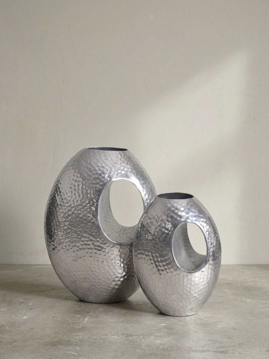 Seitenprofil der modernen Tischvase aus gehämmertem Aluminium, das ihre schlanke, organische Form und die silberne Oberfläche betont._
